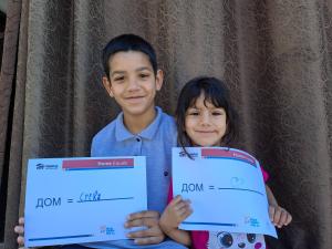 Children smiling holding a sign