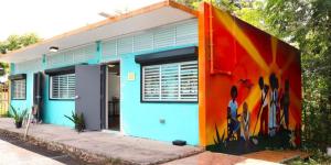 A small building with a bright orange mural painted on the side serves as a solar-powered "energy hub" for the community.