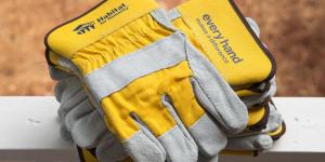 Close-up of yellow Habitat-branded work gloves on a porch railing.