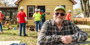 Robert smiling in front of his home with Habitat volunteers in the background