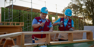 Lowe's employees in red vests hammering on build site for Carter Work Project 2023