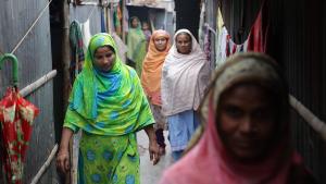 Several women in Bangladesh walk through an alleyway together.