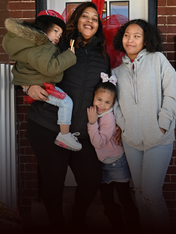 Mother with her three kids smiling by their front door