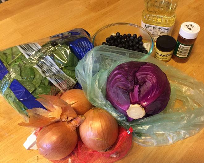 Onions, cabbage, spinach, berries and spices on a table.