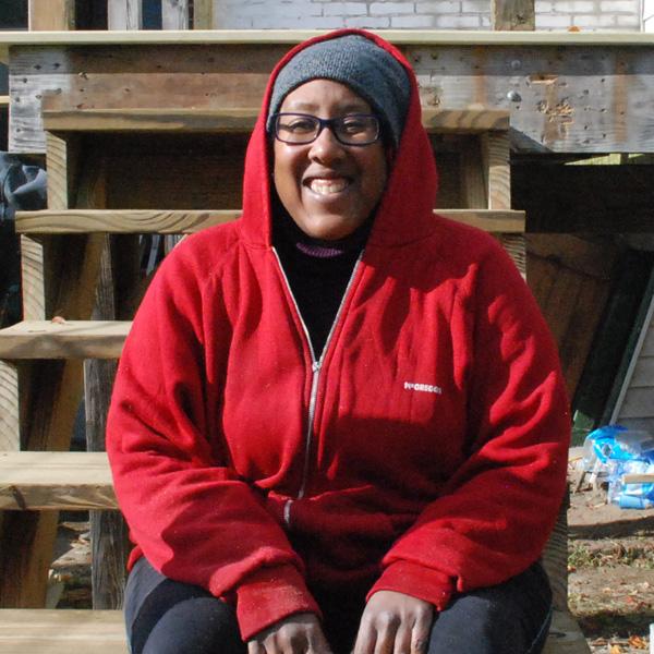 Marguerite in red hoodie sitting on unfinished stairs.