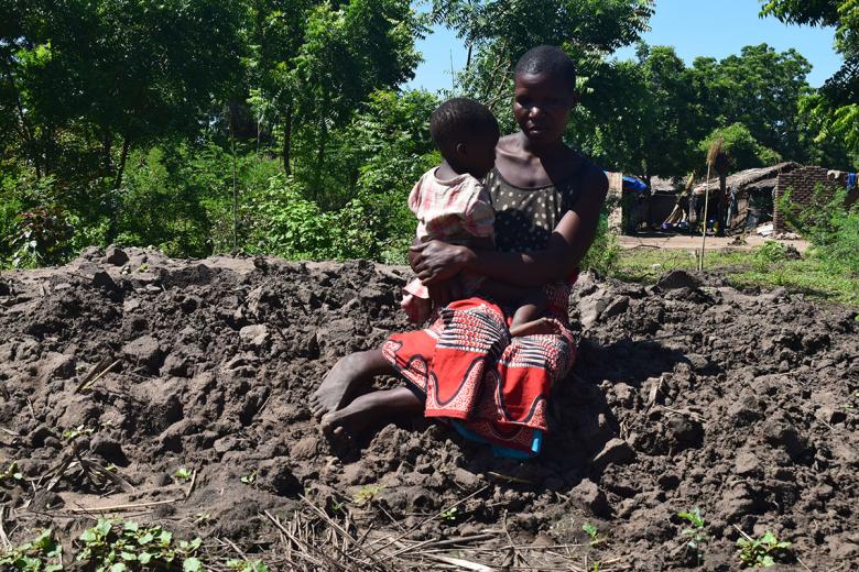 Photo: Grace sitting on mud where her house used to stand before it was taken by floods