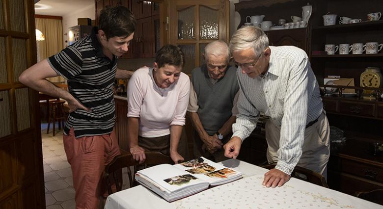 Jerzy, Alicja and family looking at a photo album.