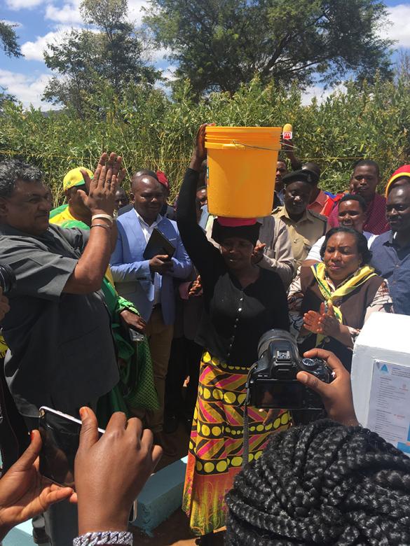 Photo: a Sangara Village resident carrying water from the new water point