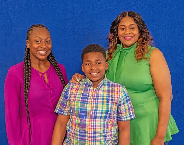 Eno and her children in front of a blue background.