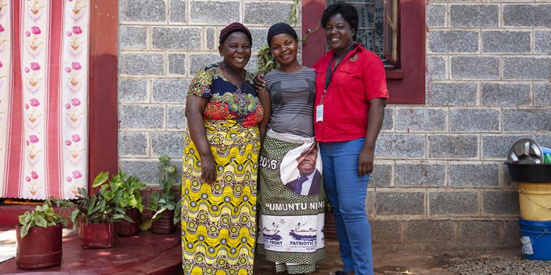 Lucy and community leader in front of Lucy's home