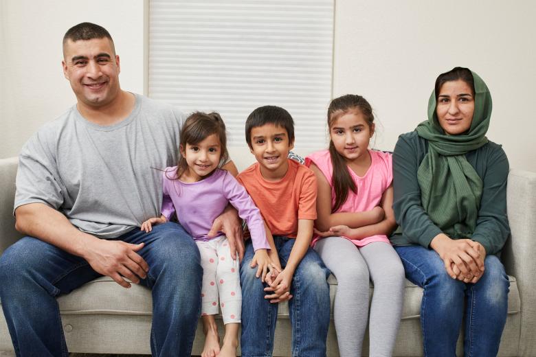 A family of five poses for a portrait on the couch. 