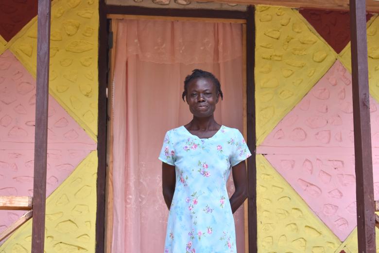 Altide stands in front of her home.