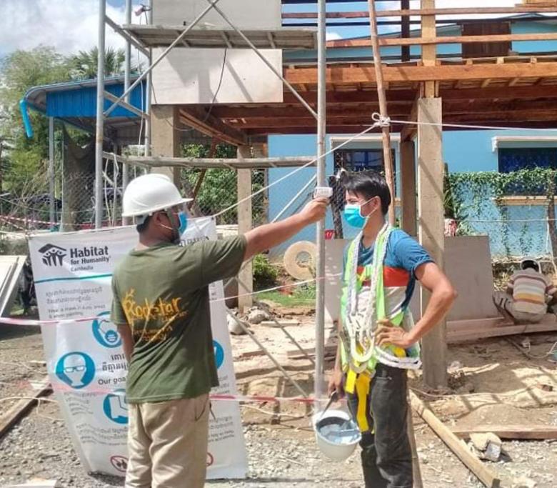 A Cambodian construction worker having his temperature taken at the worksite.