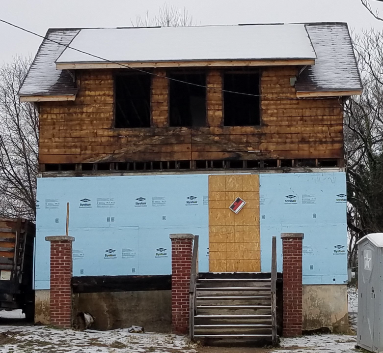 Condemned two-story home with missing siding.