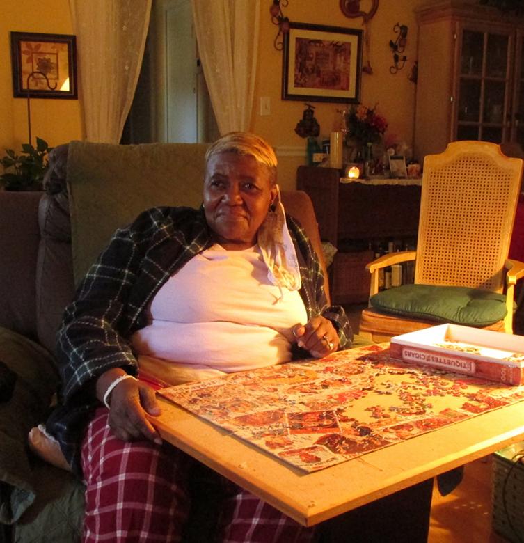 Zadie sits in front of a table with an unfinished puzzle, relaxing in her home.