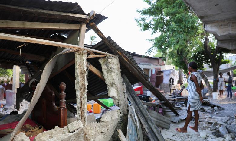 Photo taken by Nadia Todres of Hatian woman standing in front of the rubble of a collapsed home.