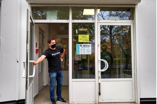 The front of the Poland ReStore. A volunteer is holding open the door and looking out.