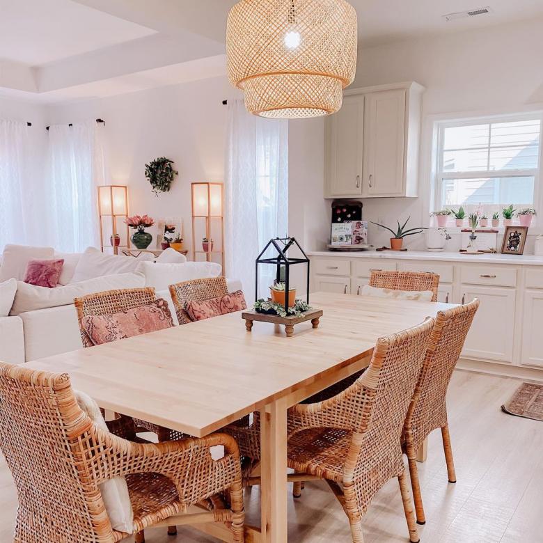 Wooden chairs centered around a long wooden table in a brightly lit kitchen.