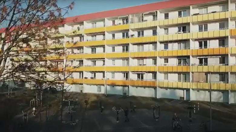 Large apartment building with red roof and yellow balconies