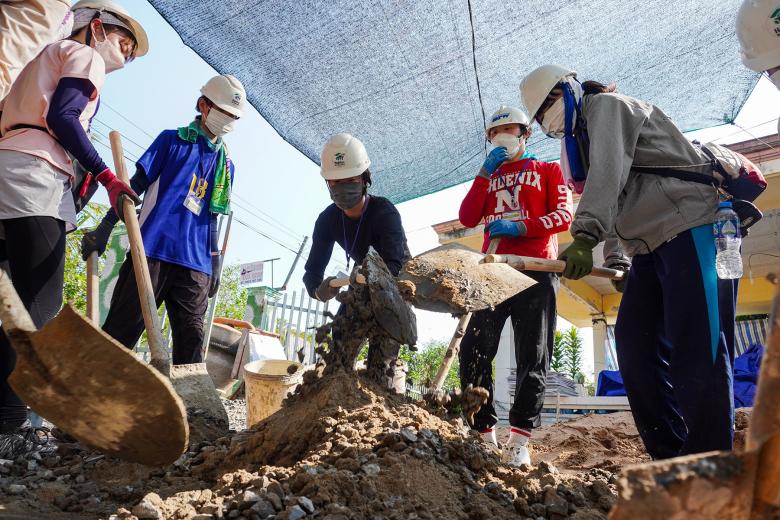 Japanese volunteers mix cement and clear bricks