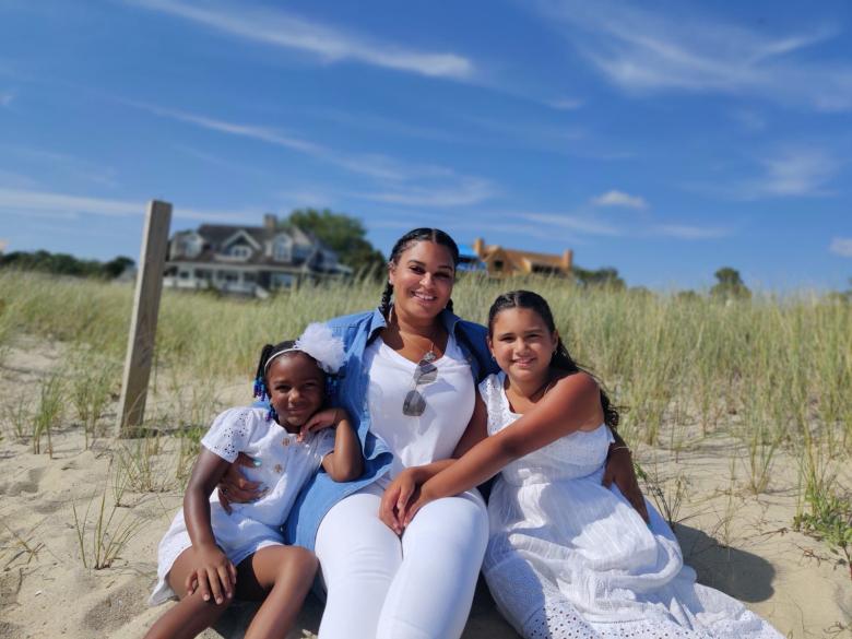 Mom and two daughters sitting on beach.