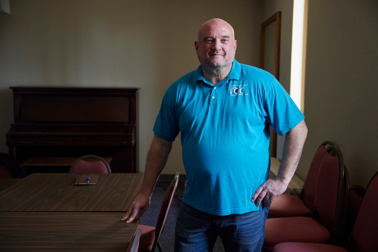 A man in a blue shirt inside a conference room.