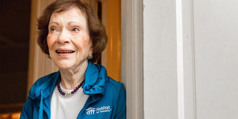 Rosalynn Carter smiling wearing a blue Habitat for Humanity jacket.