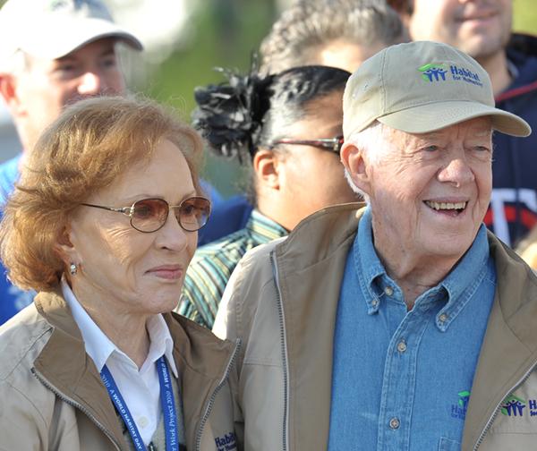 President Jimmy Carter wearing a Habitat hat and smiling next to his wife, Rosalynn Carter.